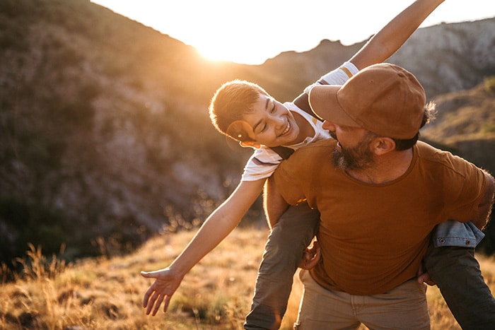 Father giving child piggyback ride outdoors in contact section at Smile By Design Orthodontics in Durango, Cortez, and Pagosa Springs, CO