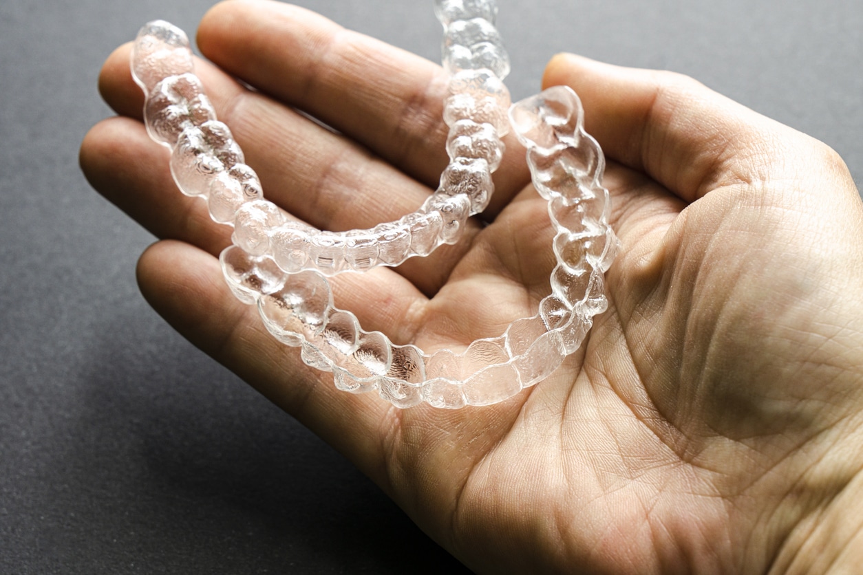 Clear aligners held in hand in Invisalign section at Smile By Design Orthodontics in Durango, Cortez, and Pagosa Springs, CO